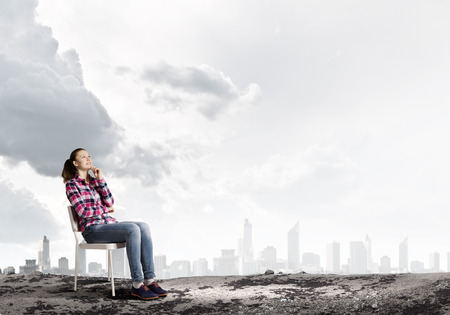 Young girl sitting in chair against city backgroundの写真素材