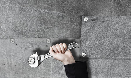 Close up of businessman hand fixing mechanism with spannerの写真素材