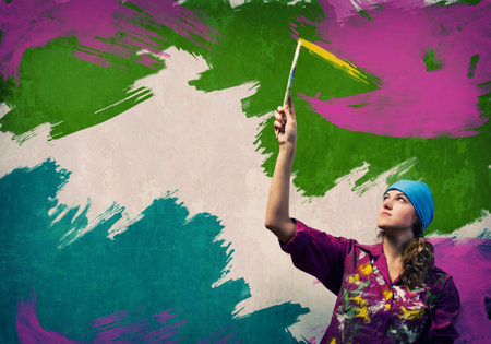 Young woman painting wall in colors with brushの写真素材