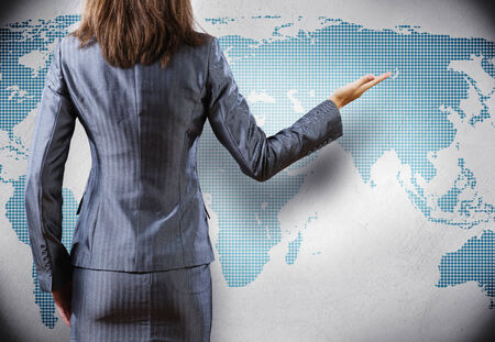 Rear view of businesswoman and world map at backgroundの写真素材