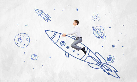 Young businessman flying in sky on drawn rocketの写真素材