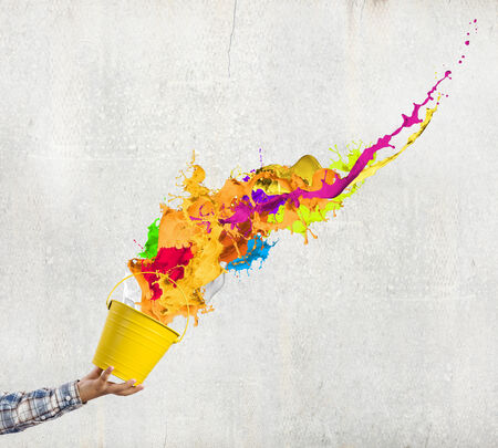 Close up of hand splashing colorful paint from bucketの写真素材
