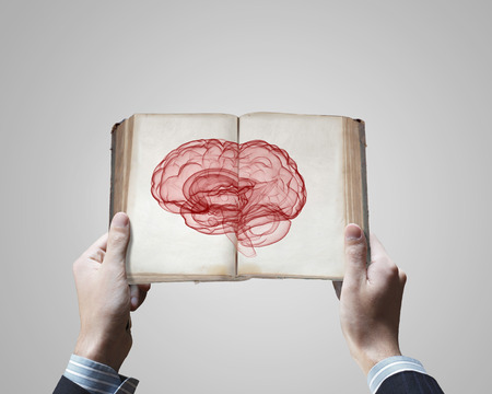 Close up of male hands holding opened book with brain pictureの写真素材