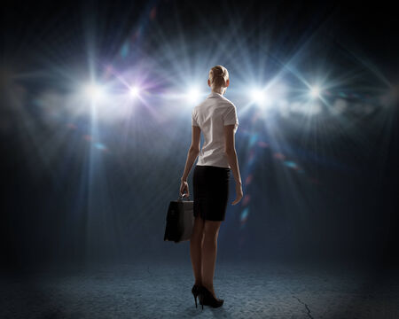 Rear view of businesswoman standing in lights of stageの写真素材
