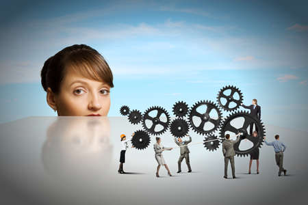 Businesswoman looking from under the table at businessteamの写真素材