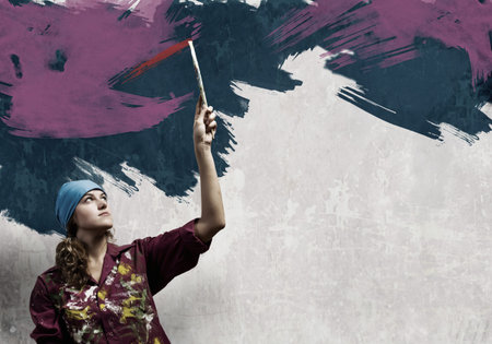 Young woman painting wall in colors with brush