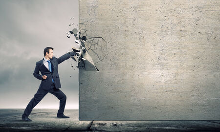 Businessman breaking stone wall with karate punchの写真素材