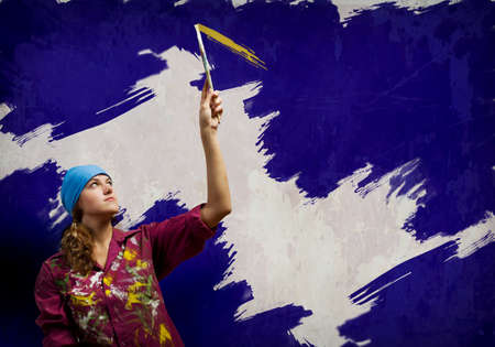 Young woman painting wall in colors with brushの写真素材