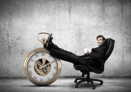 Young handsome businessman sitting in chair with cupの写真素材