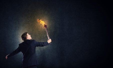 Young businessman holding burning torch in handの写真素材