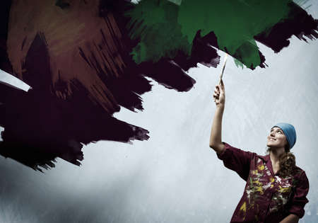 Young woman painting wall in colors with brushの写真素材