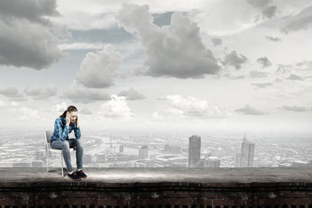 Young woman in casual sitting on in chair on top of buildingの写真素材