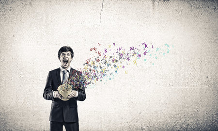 Young businessman holding yellow bucket with colorful letters