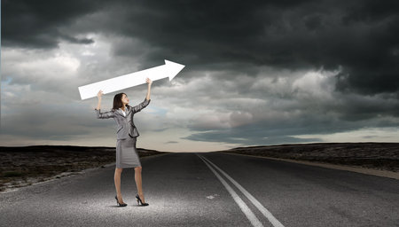 Young businesswoman in suit with increasing arrow in hand
