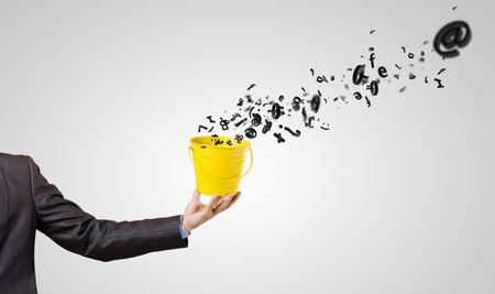 Close up of hand holding yellow bucket with letters