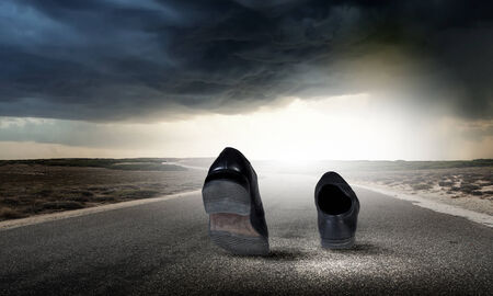 Pair of black shoes walking on roadの写真素材