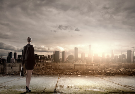 Rear view of businesswoman looking at ruins of cityの写真素材