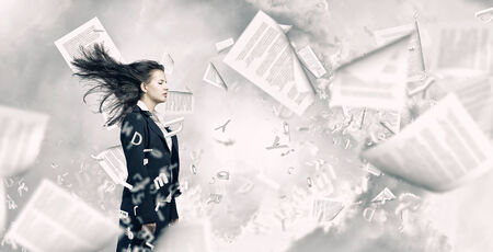 Young businesswoman with closed eyes and wind blowing in her faceの写真素材