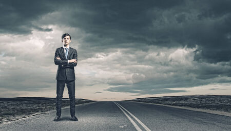 Young handsome businessman standing on asphalt roadの写真素材