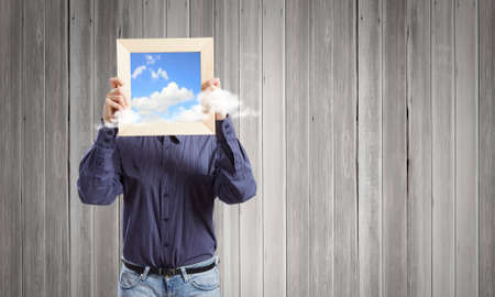Young woman in shirt with wooden frame in handsの写真素材