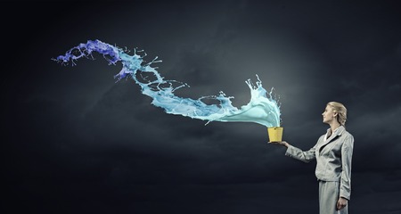 Young businesswoman holding bucket with paint splashesの写真素材