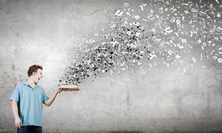 Young man with opened book in handsの写真素材