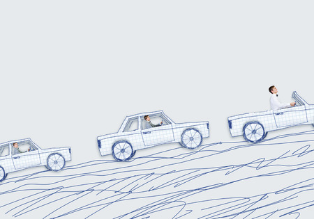 Young man driving car made of sheet of paperの写真素材