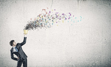 Young businessman holding yellow bucket with colorful lettersの写真素材
