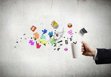 Close up of businessman holding white cup with icons flying outの写真素材