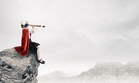 Cute supergirl of school age with looking in spyglassの写真素材