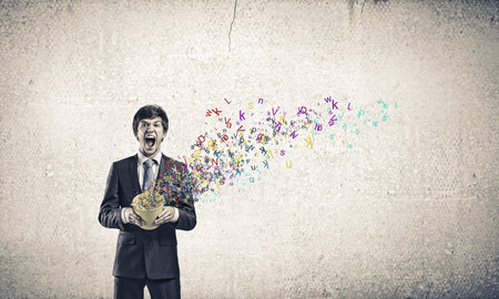 Young businessman holding yellow bucket with colorful letters