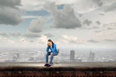 Young woman in casual sitting on in chair on top of buildingの写真素材