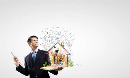 Young businessman holding paint brush in handの写真素材