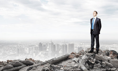 Young businessman standing on ruins of buildingの写真素材