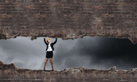 Young engineer woman lifting brick wall above headの写真素材