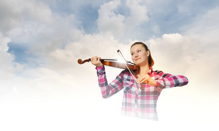 Young pretty girl in casual playing violinの写真素材