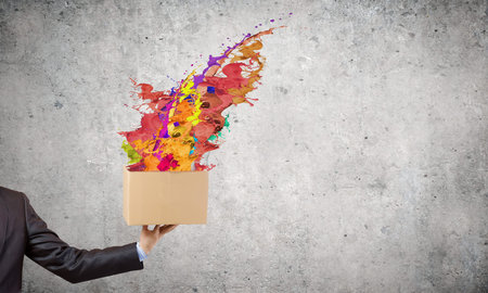 Close up of hand holding carton box with colorful splashes