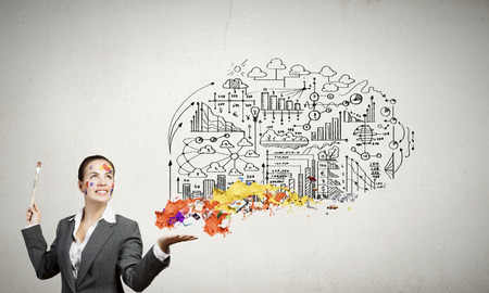 Young attractive businesswoman with paint brush and colorful business sketchesの写真素材