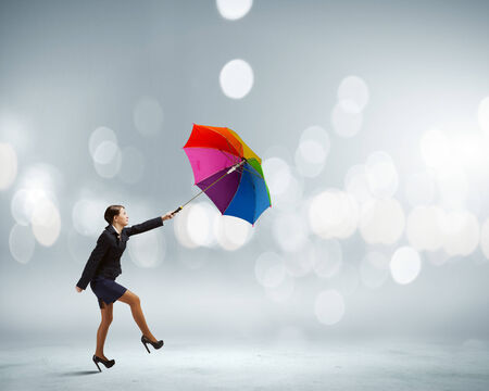 Young businesswoman walking on roof with colorful umbrellaの写真素材