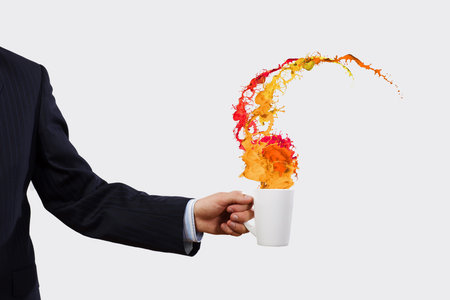 Close up of businessman holding white cup with splashes flying out