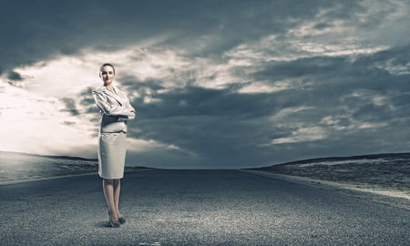 Young confident businesswoman standing on asphalt roadの写真素材