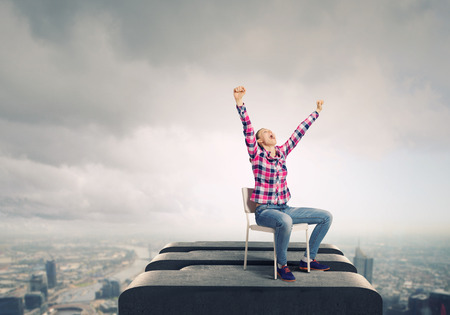 Young woman in casual with arms up celebrating successの写真素材