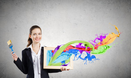 Young woman holding wooden frame with colorful splashesの写真素材