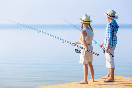 Boy and girl with fishing rods fishing together from a pierの写真素材