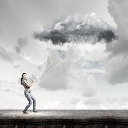 Young woman in casual catching cloud with ropeの写真素材