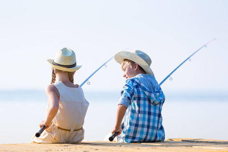 Boy and girl with fishing rods fishing together from a pierの写真素材