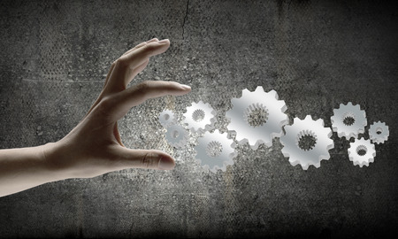 Close up of businesswoman hand and cogwheel mechanismの写真素材