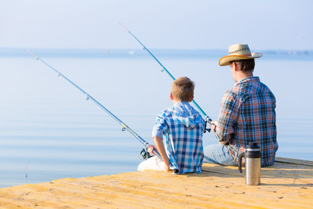 boy and his father fishing together from a pier