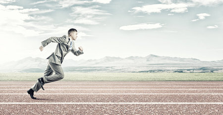 Young businessman in suit running on stadium track