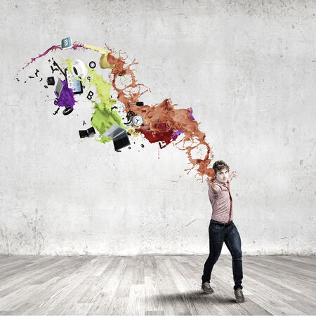 Young man in casual throwing colorful paint splashesの写真素材